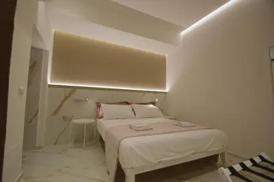a small white bedroom with a bed and a table at ARIOSTO HOME in Palermo