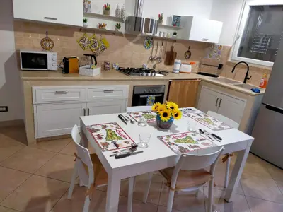 a kitchen with a white table with chairs and a white table sidx sidx at Casetta Matotta, casa vacanze a Mondello - Palermo in Mondello