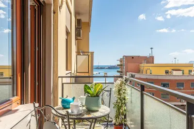 a table on a balcony with a view of the water at La Cassatella family home in Palermo