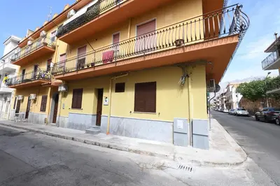 a yellow building with a balcony on a street at NONNO PEPPE Suites 1, 2 & 3 in Terrasini