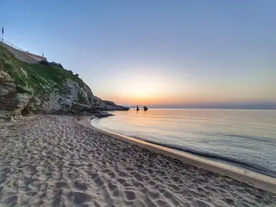 a sandy beach with a sunset in the ocean at NONNO PEPPE Suites 1, 2 & 3 in Terrasini