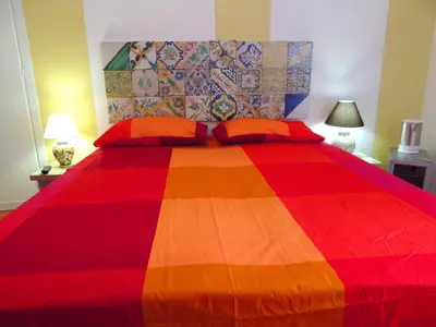 a bedroom with a colorful bed with two orange pillows at In Itinera in Palermo