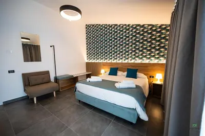 a hotel room with a bed and a chair at New River Hotel in Borgetto