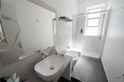 a white bathroom with a toilet and a sink at New River Hotel in Borgetto