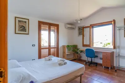 a bedroom with a bed and a desk and a chair at Casa Margherita Cefalù - Villa con accesso privato al mare in Cefalù