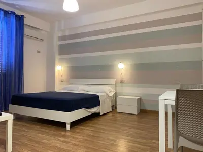 a bedroom with a bed and a striped wall at Marina di Petrolo Apartments in Castellammare del Golfo