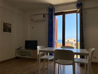 a dining room with a table and chairs and a window at Marina di Petrolo Apartments in Castellammare del Golfo
