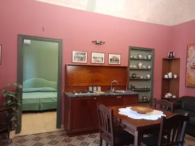 a kitchen with a table and a sink and a bedroom at Casa Castelli Holiday Apartment in Bagheria