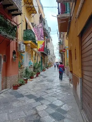 an alley in an old town with people walking down it at Casa Mauro in Palermo