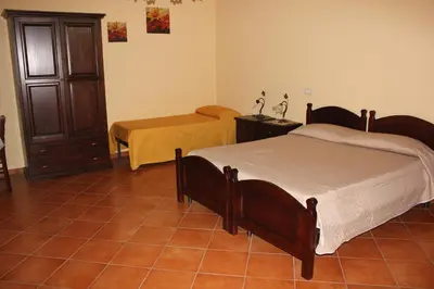 a bedroom with two beds and a table in it at B&B Ulivo in Trabia