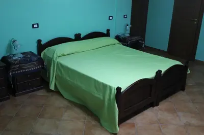 a bedroom with a large bed with a green blanket at B&B Ulivo in Trabia