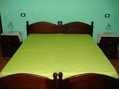 a bedroom with a bed with a green comforter at B&B Ulivo in Trabia