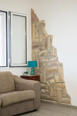 a living room with a couch and a stone wall at Villa Mare E Monti in Castellammare del Golfo