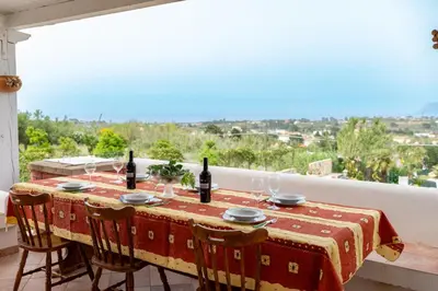 a table with wine bottles and glasses on a balcony at Villa Mare E Monti in Castellammare del Golfo