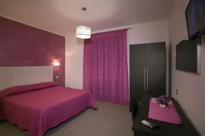 a bedroom with a pink bed and a tv at Rotte e Sentieri B&B in Castelluzzo