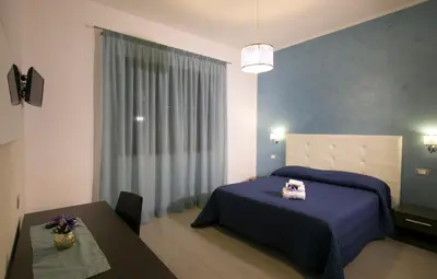 a bedroom with two beds and a table and a window at Rotte e Sentieri B&B in Castelluzzo