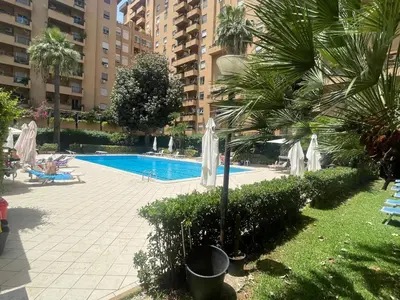 a swimming pool with palm trees and umbrellas at Sara House Palermo in Palermo