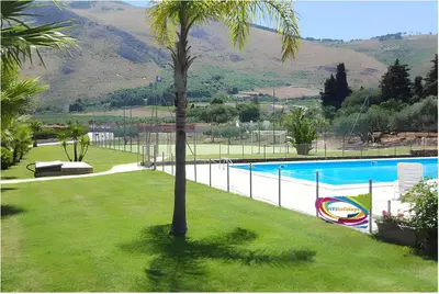 a palm tree in a yard next to a swimming pool at ViViHolidays in Castellammare del Golfo