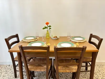 a wooden table with chairs and plates and a vase of flowers at Ekry Apartment in Palermo