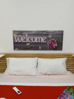 a bed with a welcome sign on the wall at Amalcamo Apartments in Alcamo