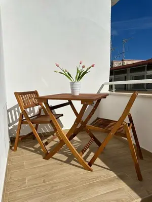a wooden table and chair on a balcony with a potted plant at Amalcamo Apartments in Alcamo