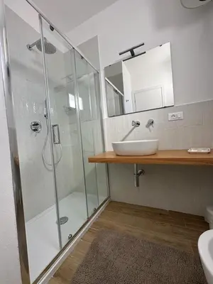 a bathroom with a glass shower and a sink at Amalcamo Apartments in Alcamo
