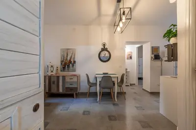 a dining room with a table and chairs and a clock at Casa delle Travi by Wonderful Italy in Palermo