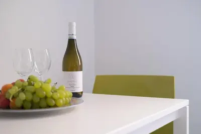 a bottle of wine sitting on a table with a plate of grapes at Porta dei Mori Apartment in Palermo
