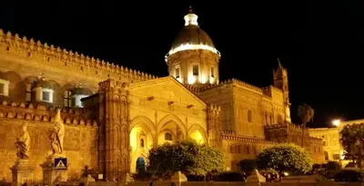 a large building with a clock tower at night at Porta dei Mori Apartment in Palermo