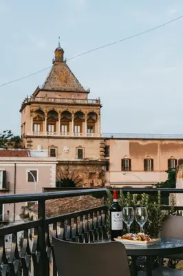 a table with two glasses of wine on a balcony at Porta dei Mori Apartment in Palermo