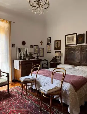 a bedroom with a bed and two chairs and a chandelier at A Casa da Paola in Caccamo