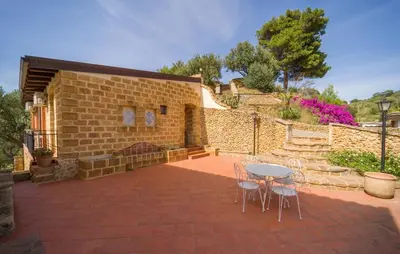 a patio with a table and chairs and a brick wall at Casale Del Golfo in Alcamo