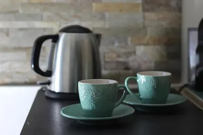 two green cups on a table with a tea pot at A' Nica room in Palermo