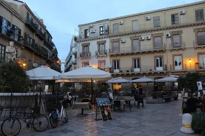 an outdoor patio with tables and umbrellas in front of buildings at A' Nica room in Palermo