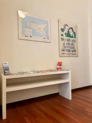 a bench in front of a white wall with a poster at Castelnuovo Rooms #Politeama in Palermo