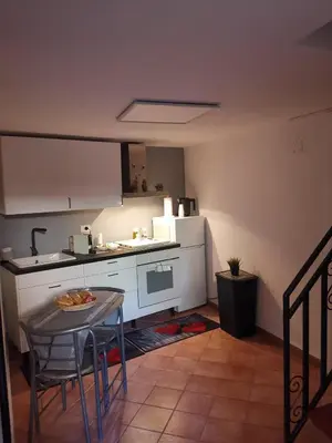 a small kitchen with a table and a white refrigerator at casa centro storico O Capu in Palermo