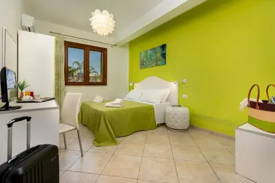 a bedroom with a bed with a green wall at B&B Armonie in San Vito lo Capo