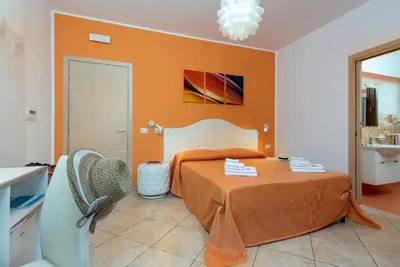 a bedroom with a bed with an orange wall at B&B Armonie in San Vito lo Capo