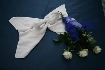 a white towel and a bouquet of flowers on a bed at B&B Armonie in San Vito lo Capo