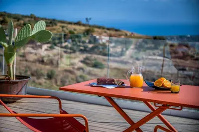 a red table with two glasses of orange juice on a balcony at Villa Pharus Scopello in Scopello