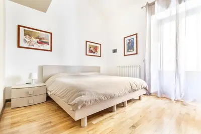 a white bedroom with a bed and a wooden floor at B&B Porta delle Madonie in Campofelice di Roccella