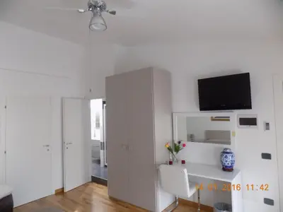 a white living room with a tv on the wall at B&B Porta delle Madonie in Campofelice di Roccella