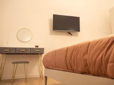 a couch with a table and a tv on the wall at La Premiere Suite - Teatro Massimo Palermo in Palermo