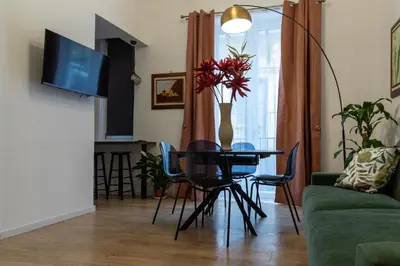 a living room with a table and chairs and a television at La Premiere Suite - Teatro Massimo Palermo in Palermo