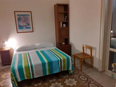 a bedroom with a bed and a chair in a room at Casa nonno Enrico in via Oreto in Palermo