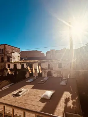 a table with chairs on top of a building with the sun at Casa nonno Enrico in via Oreto in Palermo