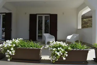a patio with two white chairs and white flowers at b&b Lastracu in Castellammare del Golfo