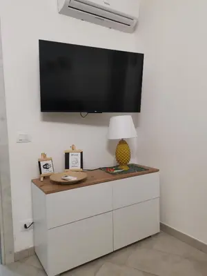 a flat screen tv on a wall with a white cabinet at La casa sotto il castello in Caccamo