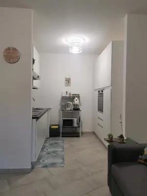 a kitchen with white walls and a living room at La casa sotto il castello in Caccamo