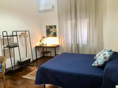 a bedroom with a blue bed and a desk with a lamp at G&G ROOMS in Palermo